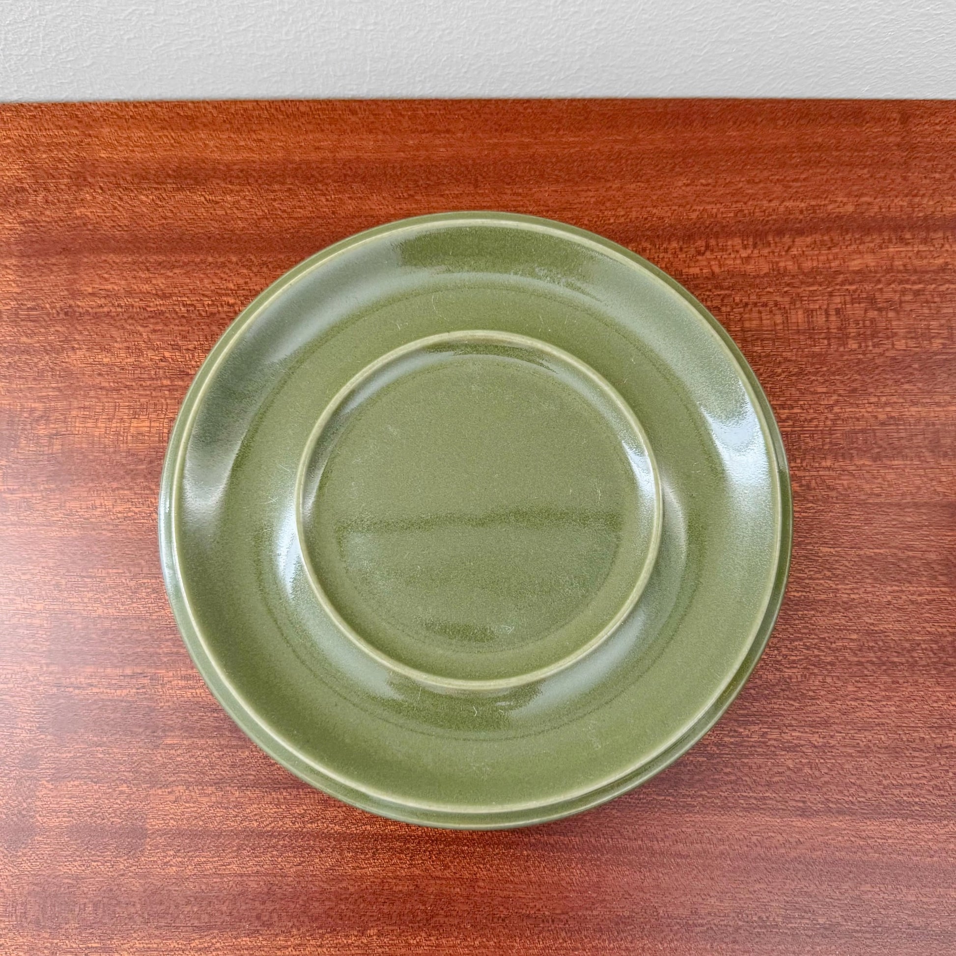 Arabia Finland Hilkka-Liisa Ahola Large Green Mug with Saucer showing the glossy hand-painted green ceramic saucer on a wooden surface, representing vintage Nordic craftsmanship.