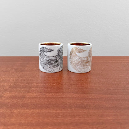 Pair of Arabia Finland Kukko Egg Cups featuring detailed hand-painted rooster designs in black and brown tones on white ceramic, showcasing vintage Scandinavian craftsmanship.