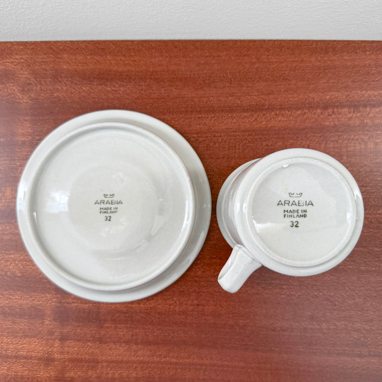 Arabia Finland Oliivi Coffee Cup with Saucer shown bottom-side up on a wooden surface, showcasing the vintage maker’s mark and minimalist design from the Nordic Wares Store collection.
