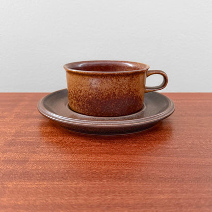 Arabia Finland Ruska Tea Cup with Saucer in a warm, mottled brown ceramic finish, showcasing classic Nordic vintage design on a wooden surface.
