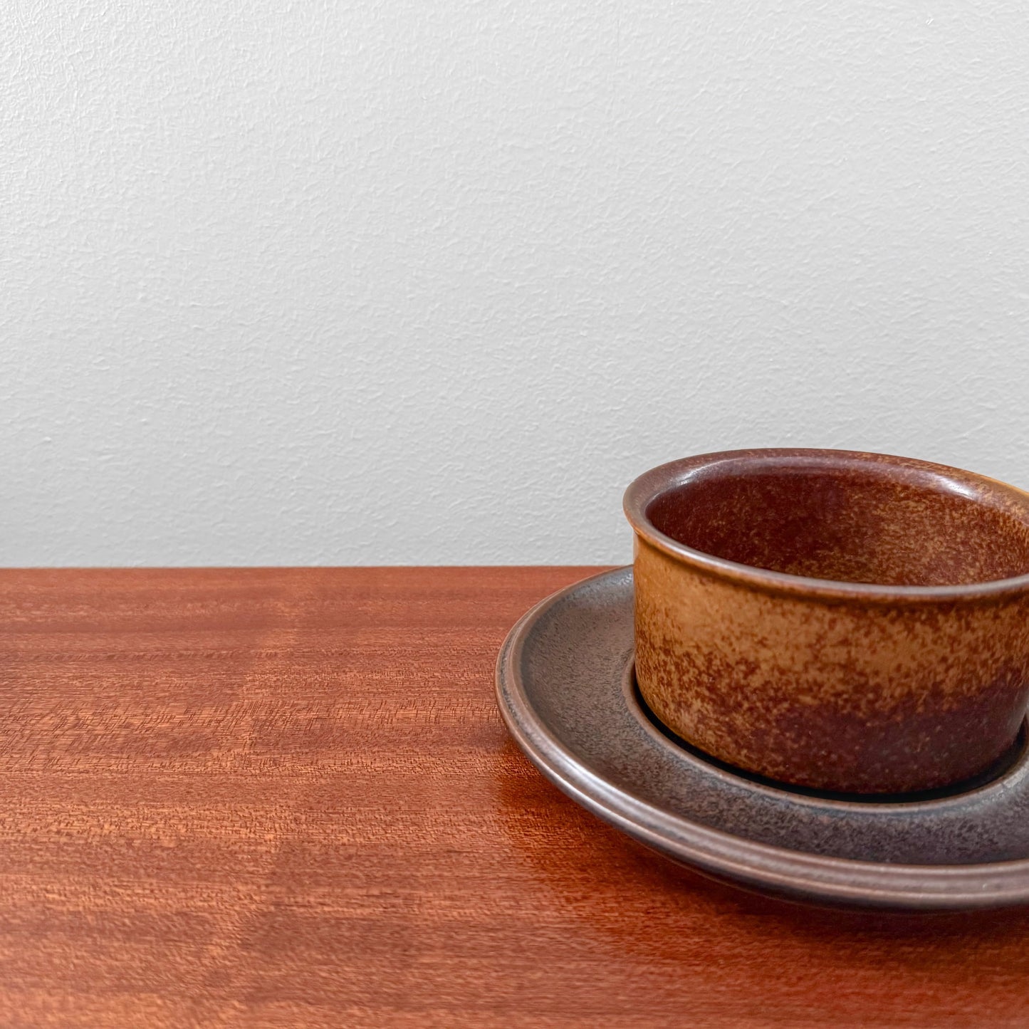 Arabia Finland Ruska Tea Cup with Saucer in a rare golden brown glaze, showcasing vintage Nordic ceramic craftsmanship on a wooden surface.