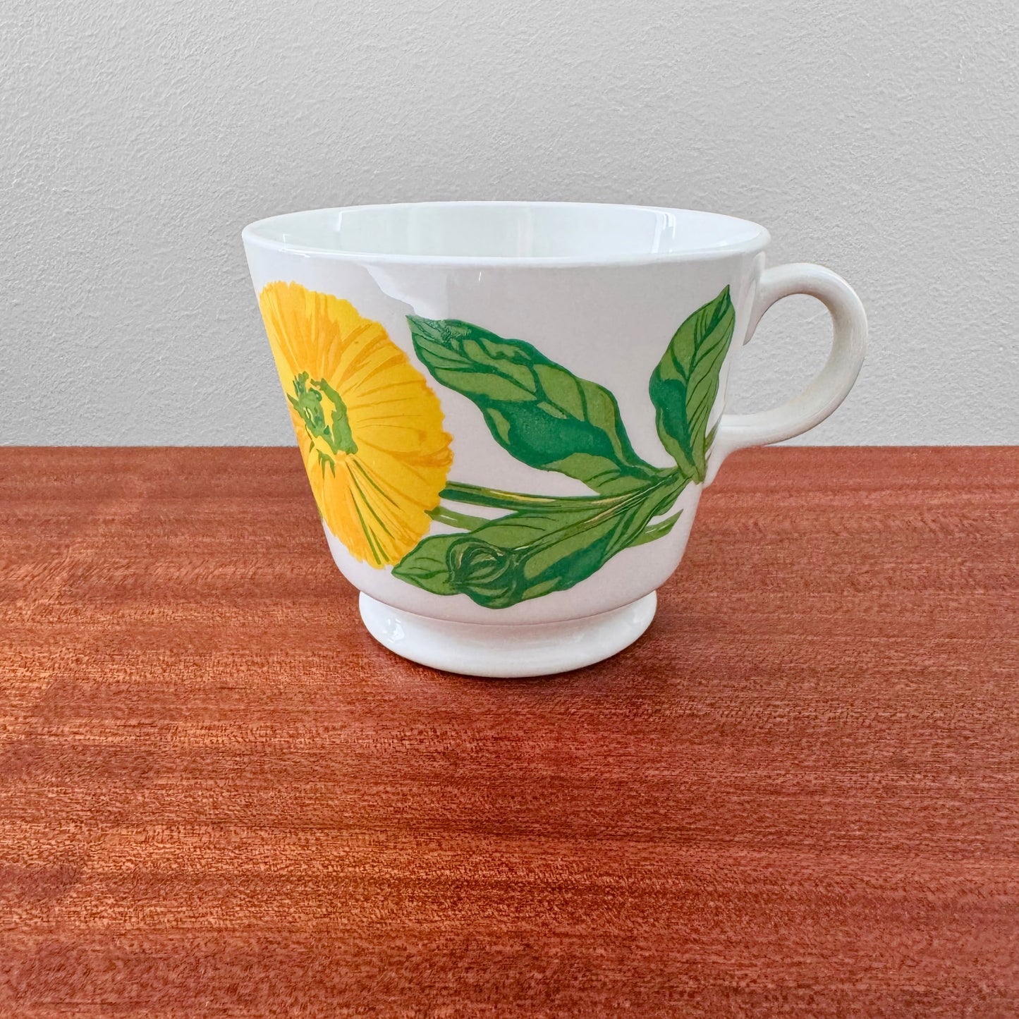 Arabia Finland Suvi Large Cocoa Cup with vibrant yellow flower and green leaves design, showcasing vintage Nordic ceramic drinkware on wooden surface.
