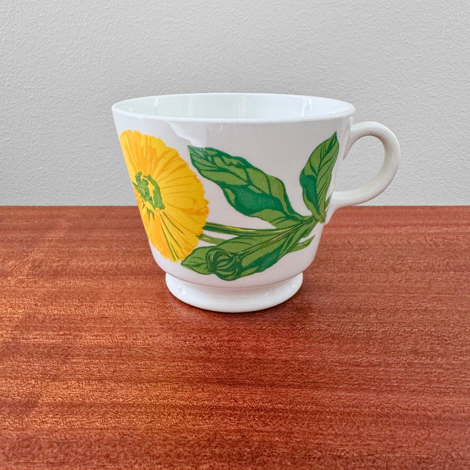 Arabia Finland Suvi Large Cocoa Cup with vibrant yellow flower and green leaves design, showcasing vintage Nordic ceramic drinkware on wooden surface.