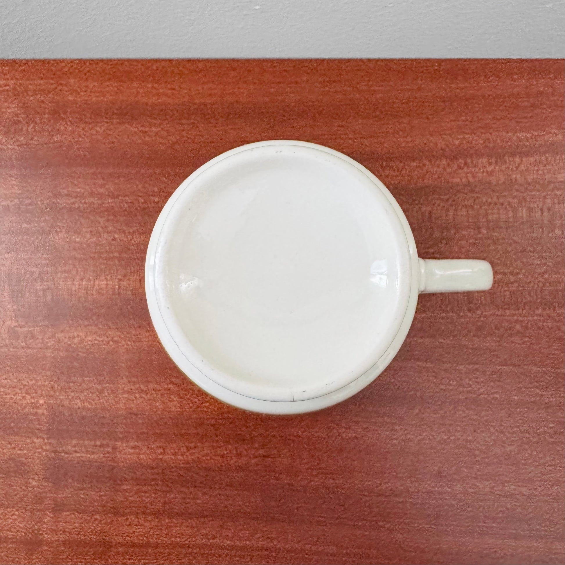 Arabia Finland Suvi Large Cocoa Cup shown from above on a wooden surface, featuring simple white ceramic design and a single handle.