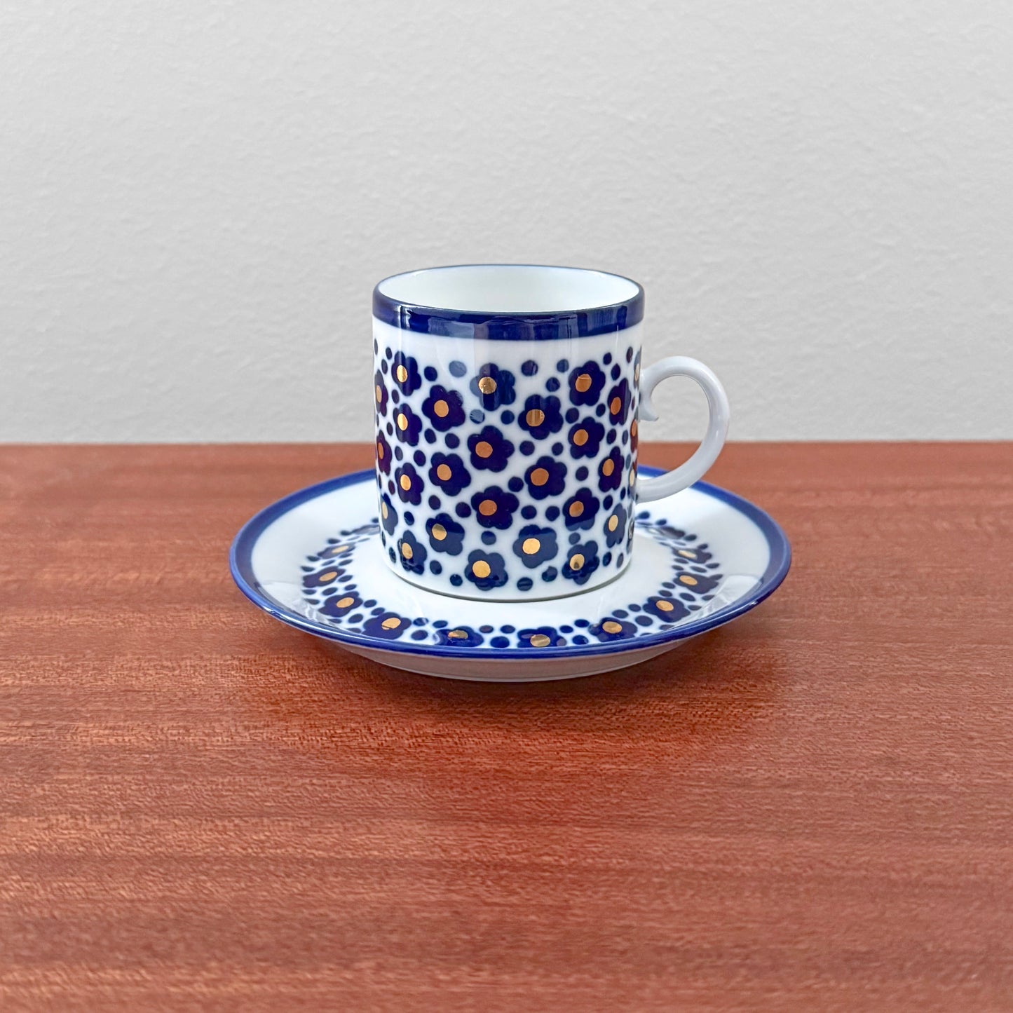Arabia Finland Virva Espresso Cup with Saucer featuring a vintage floral pattern with blue and orange flowers on white ceramic, displayed on a wooden surface.