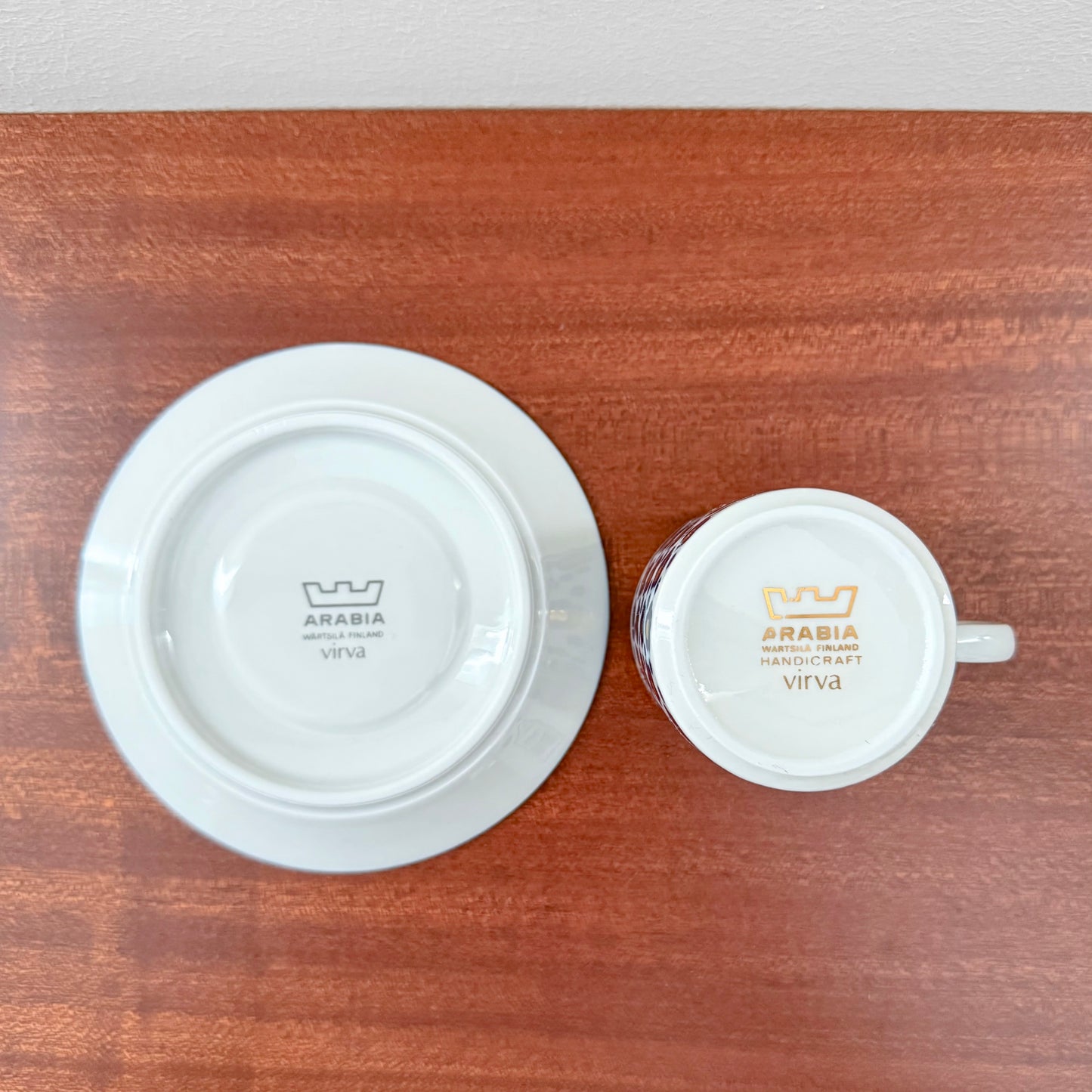 Bottom view of Arabia Finland Virva Espresso Cup with Saucer showing vintage markings on white ceramic against a wooden surface from Nordic Wares Store collection.