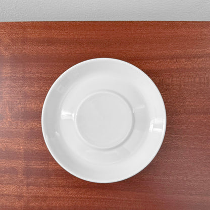 Bing & Grøndahl Hank Tea Cup Trio Set white ceramic saucer on wooden surface, showcasing minimalist Scandinavian design and craftsmanship.