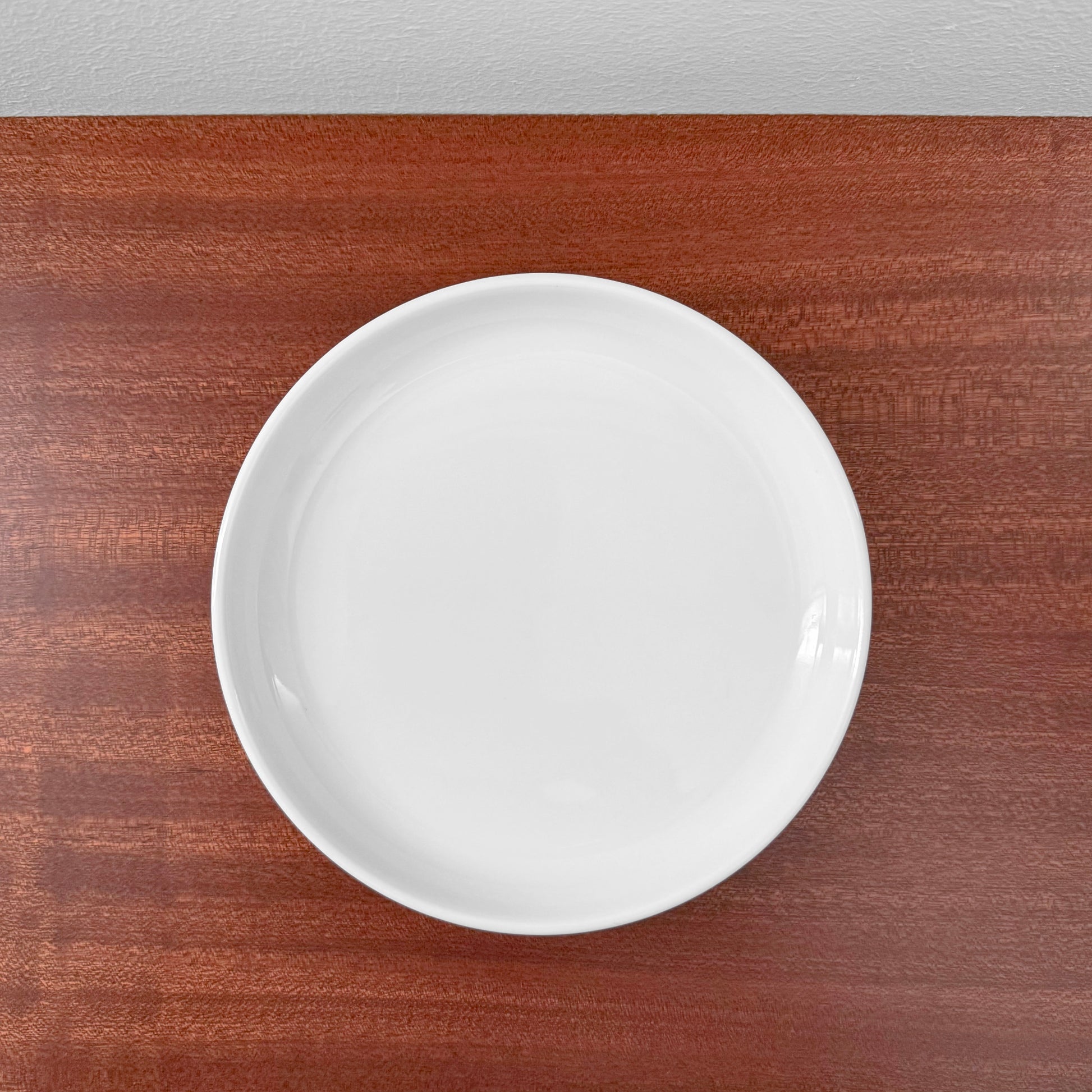 Bing & Grøndahl Hank Tea Cup Trio Set white ceramic cake plate on wooden surface, showcasing minimalist Nordic design and craftsmanship.