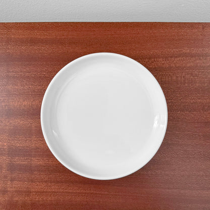 Bing & Grøndahl Hank Tea Cup Trio Set white ceramic cake plate on wooden surface, showcasing minimalist Nordic design and craftsmanship.