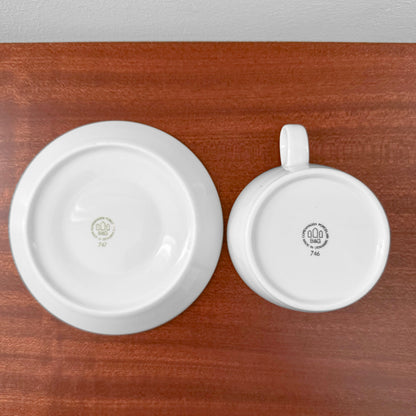Bottom view of a vintage Bing & Grøndahl Hank Tea Cup Trio Set showing maker's marks on a white cup and saucer placed on a wooden surface.