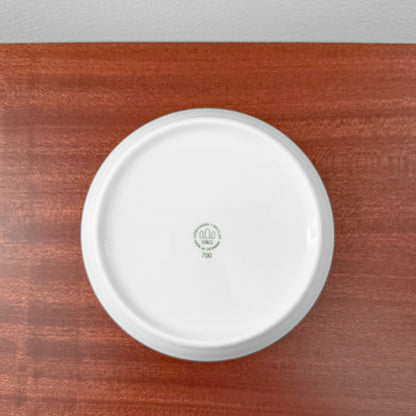 Bottom view of a white ceramic dish with a green Nordic Wares Store stamp showing markings on a wooden surface for Bing & Grøndahl Hank Tea Cup Trio Set.