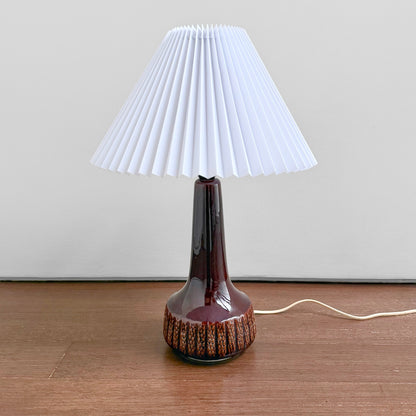 Danish Red Stoneware Table Lamp with deep red ceramic base featuring textured details and a new white plastic pleated shade, vintage Scandinavian lighting piece from the 1960s-70s.