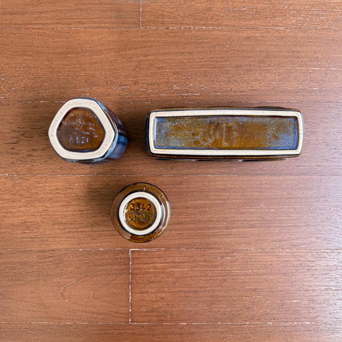 Einar Johansen Søholm Stoneware Decor Set, three ceramic decorative objects in blue brown glaze, shown from the underside on a wooden surface.