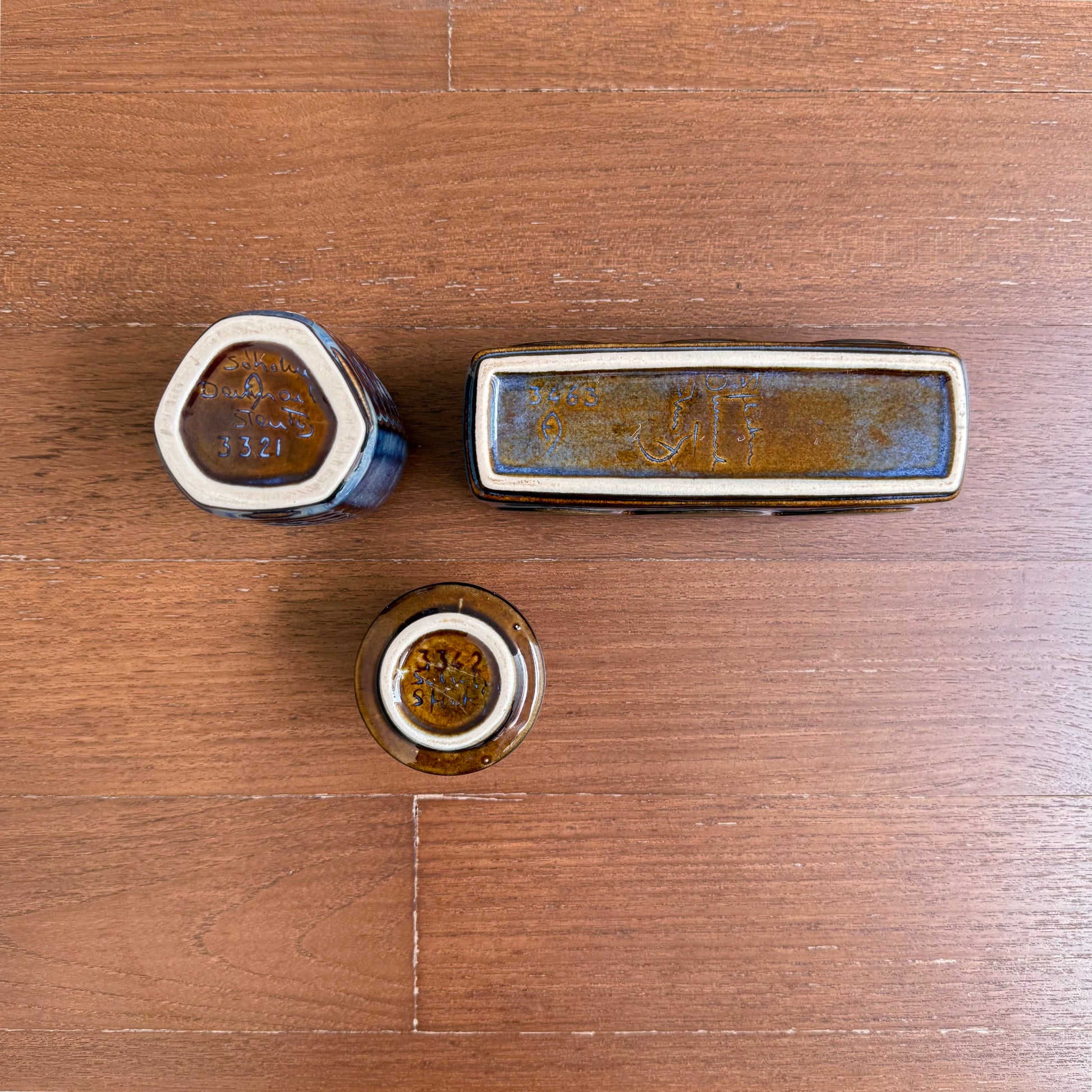 Einar Johansen Søholm Stoneware Decor Set, three ceramic decorative objects in blue brown glaze, shown from the underside on a wooden surface.