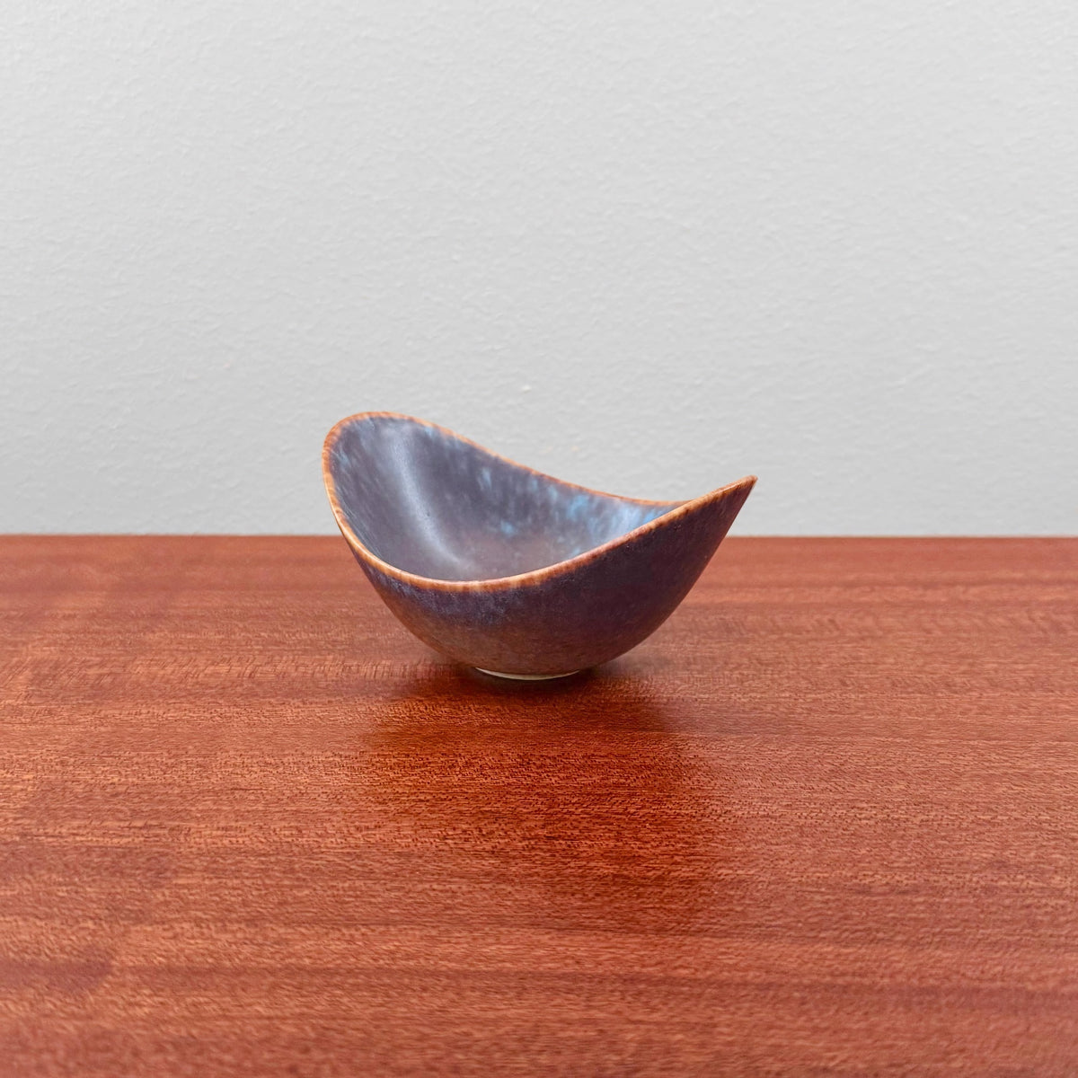 Gunnar Nylund Rörstrand ARO Small Stoneware Decorative Bowl in blue and brown glaze with an organic shape, vintage 1950s-60s Scandinavian ceramic design on wooden surface.