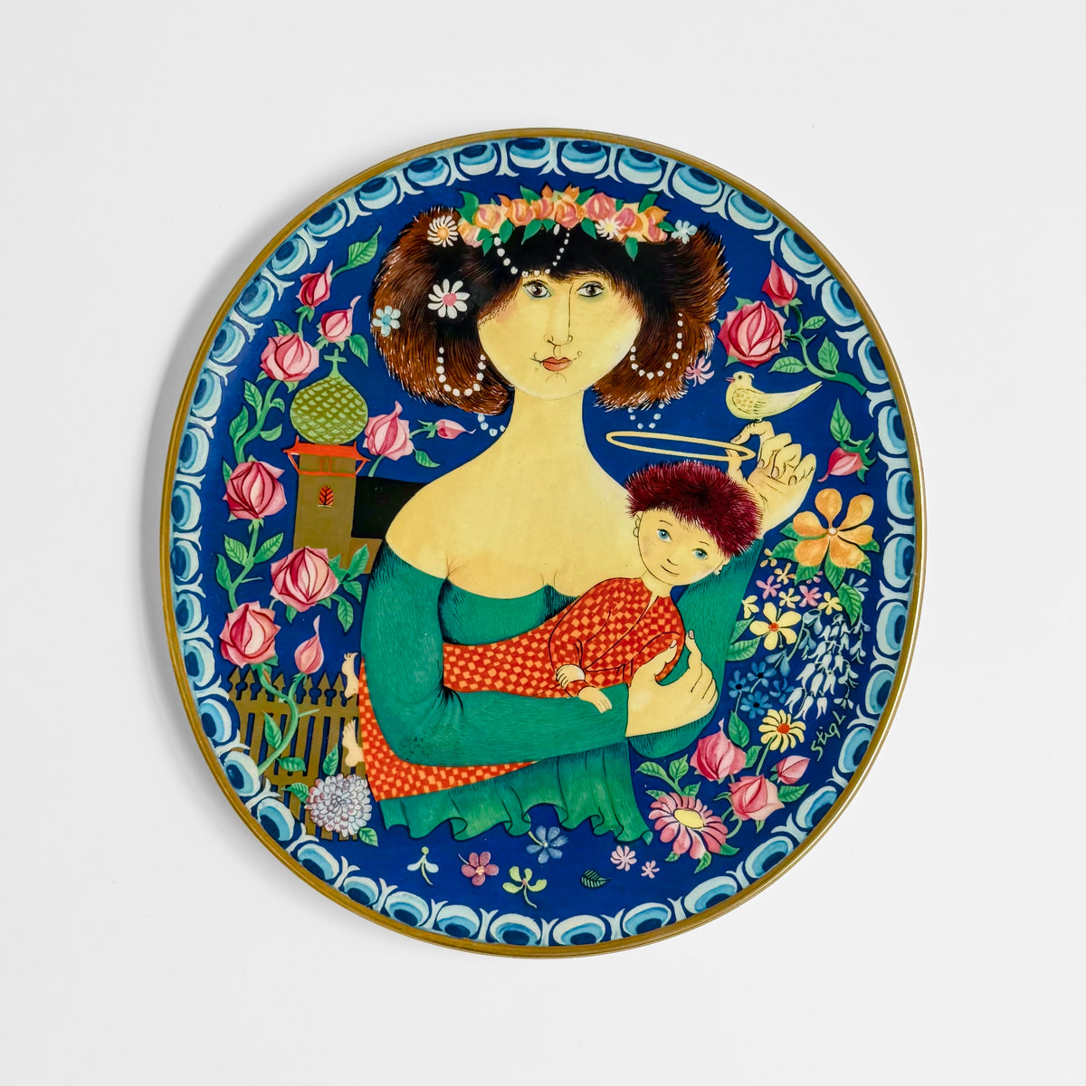 Gustavsberg Christmas Art Plates (1981-1982) decorative ceramic plate by Stig Lindberg showing a woman holding a child amid colorful flowers and Nordic folk art patterns