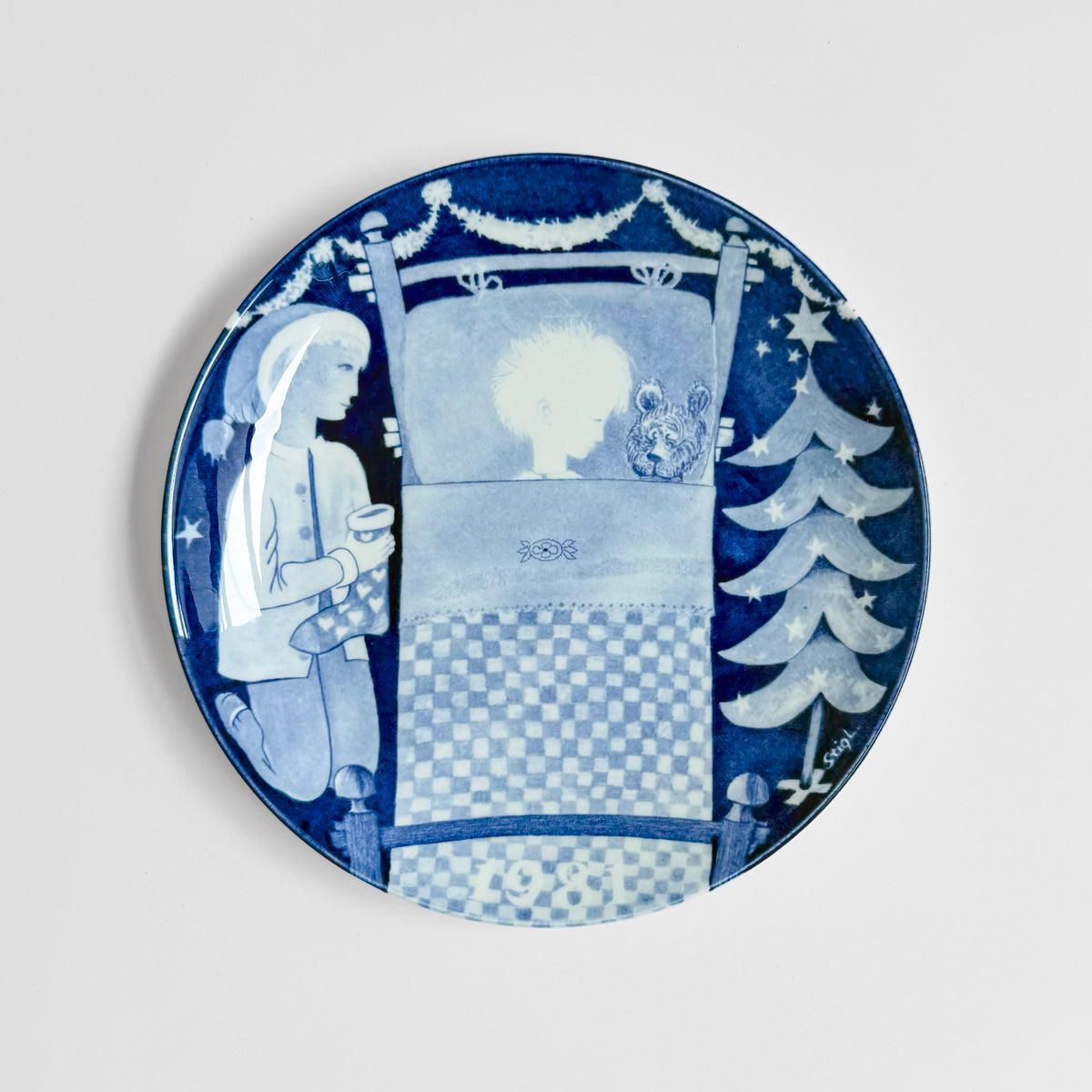 Gustavsberg Christmas Plates (1981-1985), blue and white decorative plate with Stig Lindberg winter scene featuring a girl, Christmas tree, stars, and moon