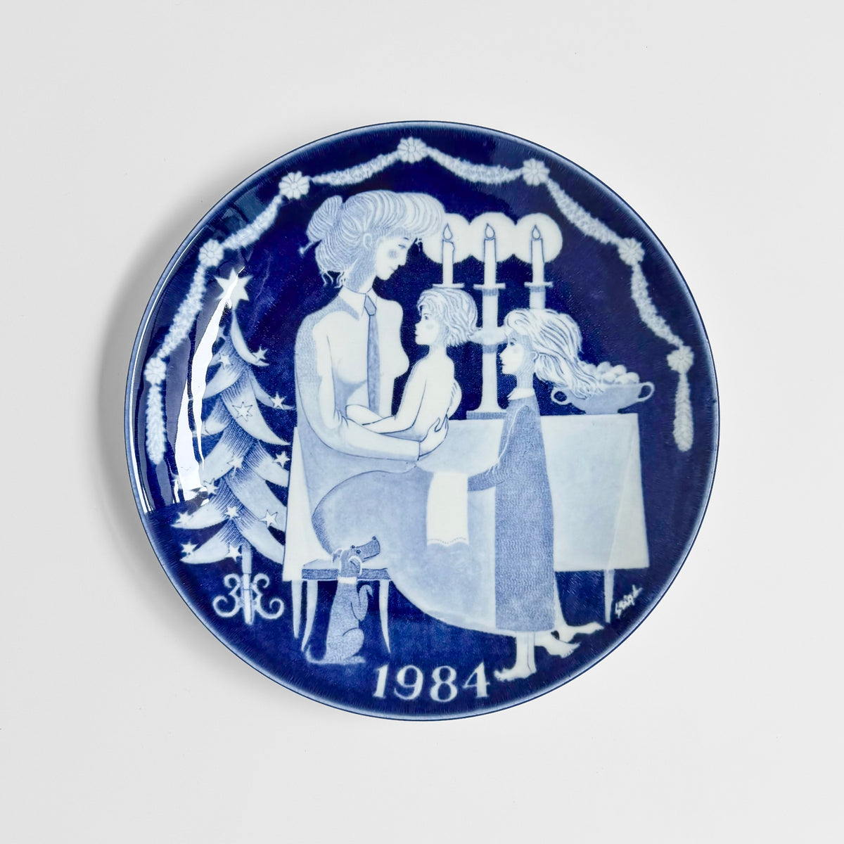 Gustavsberg Christmas Plates (1981-1985) vintage blue decorative plate by Stig Lindberg showing children around a candlelit Christmas tree dated 1984
