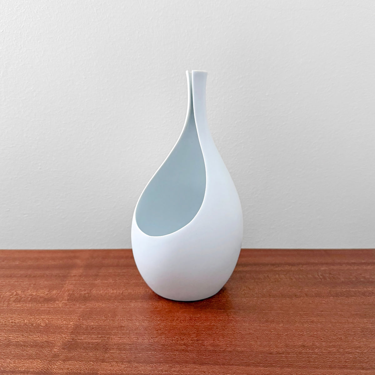 Gustavsberg Pungo White Vase (19 cm) in ceramic with a sleek sculptural form featuring a narrow neck and an open side, designed by Stig Lindberg in 1950s Sweden.