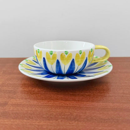 Hertha Bengtson Rörstrand Tea Cup with Saucer featuring a vibrant yellow and blue floral design on ceramic, showcasing vintage Scandinavian craftsmanship from the 1940s.