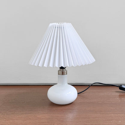 Holmegaard Carol White Opal Glass Table Lamp with a round white glass base and new plastic pleated white shade, vintage Scandinavian lighting for elegant home decor.