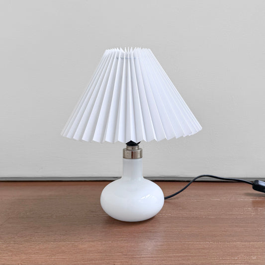 Holmegaard Carol White Opal Glass Table Lamp with a round white glass base and new plastic pleated white shade, vintage Scandinavian lighting for elegant home decor.