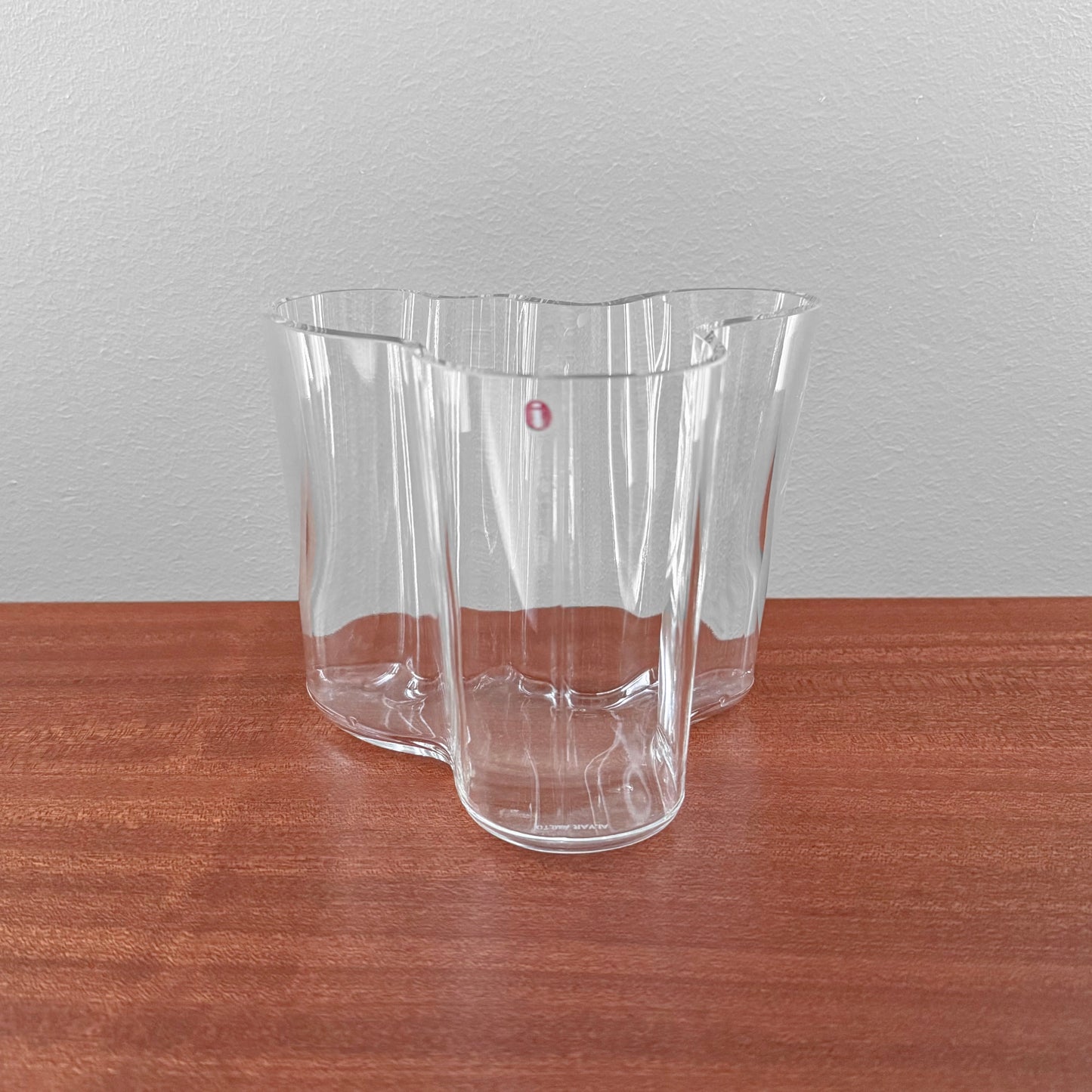 Iittala Aalto Savoy Clear Glass Vase (120 mm) designed by Alvar Aalto, featuring a fluid organic shape crafted in clear glass, displayed on a wooden surface.