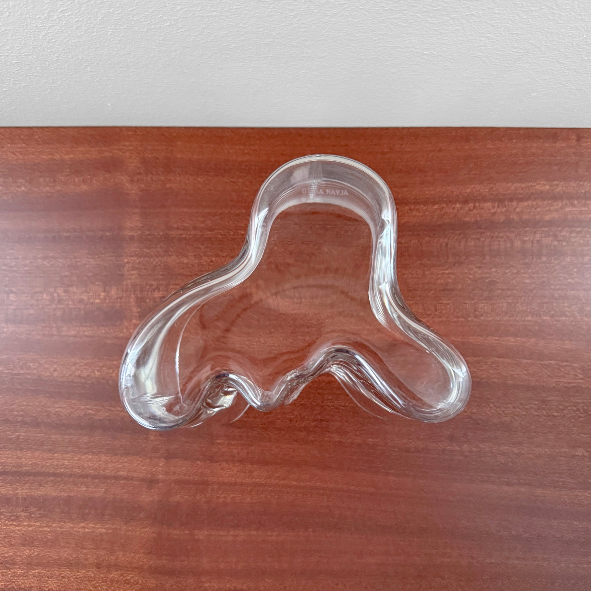 Iittala Aalto Savoy Clear Glass Vase (120 mm) featuring an organic, wavy shape made from clear glass, showcasing Scandinavian design by Alvar Aalto on a wooden surface.