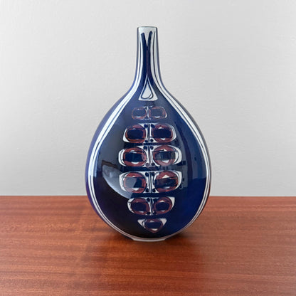 Inge-Lise Koefoed Royal Copenhagen Tenera Vase (148/2740), ceramic vase with an abstract eye motif in blue, displayed on a wooden surface.