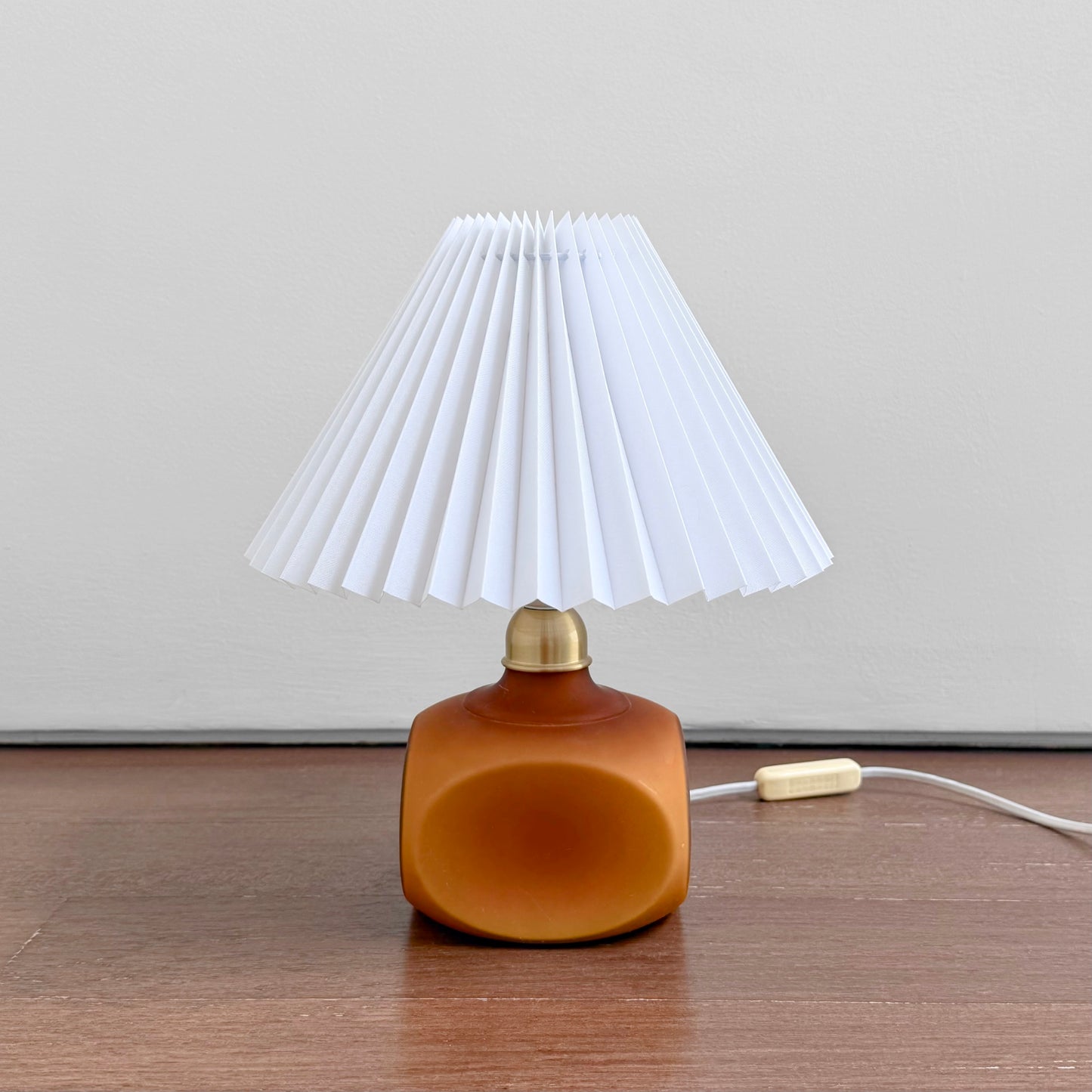 Le Klint 312 Amber Opal Glass Table Lamp with amber glass base and white pleated plastic shade, a vintage lighting piece reflecting Nordic craftsmanship and design.