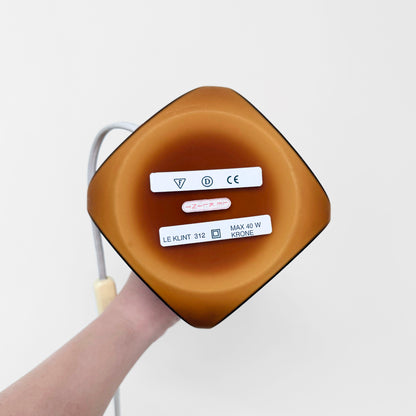 Bottom view of Le Klint 312 Amber Opal Glass Table Lamp showing amber colored glass base with labels and electrical cord attached, highlighting vintage Nordic lighting design.