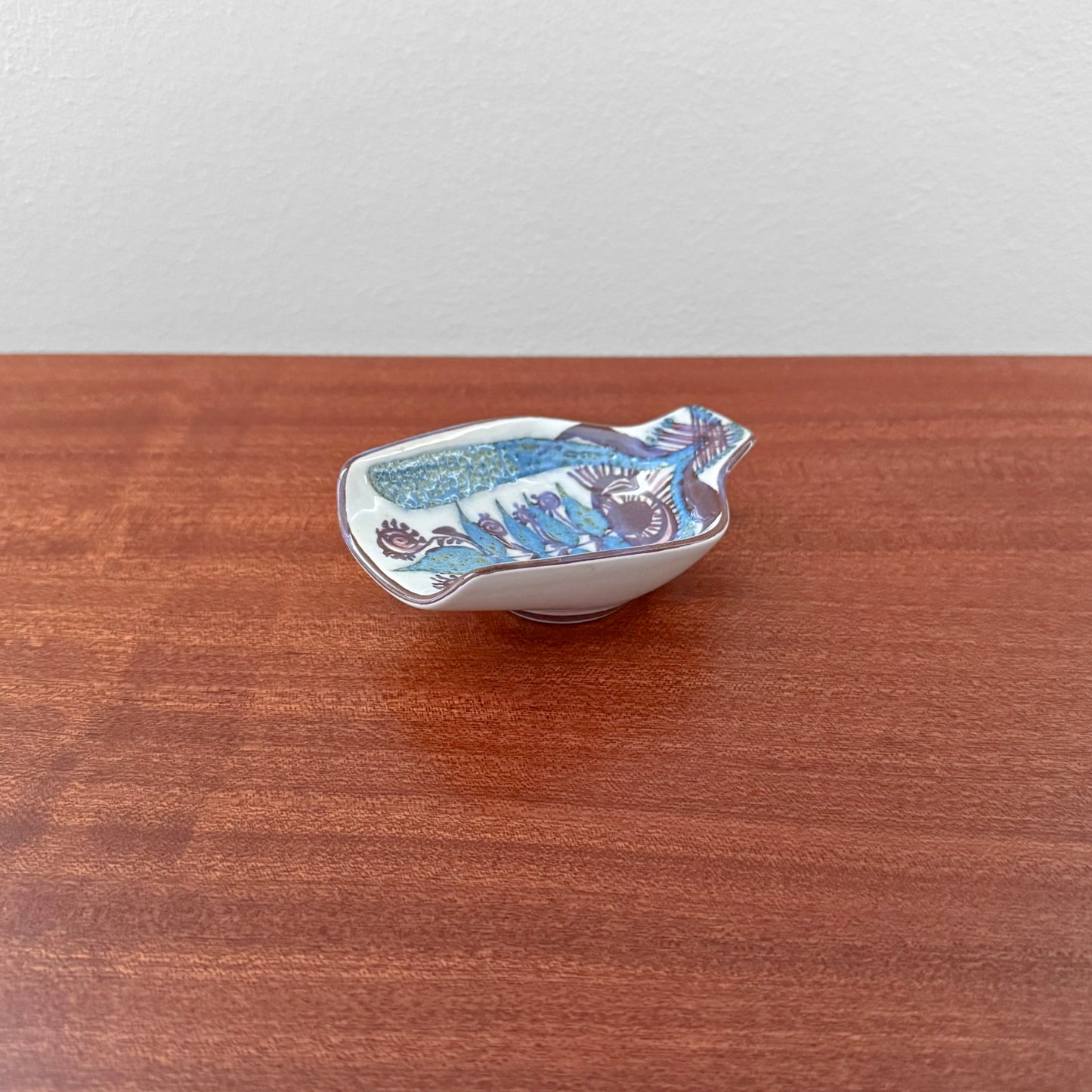 Marianne Johnson Royal Copenhagen Tenera Spoon Rest (414/2900) with stylised blue and purple floral decoration on a white ceramic dish
