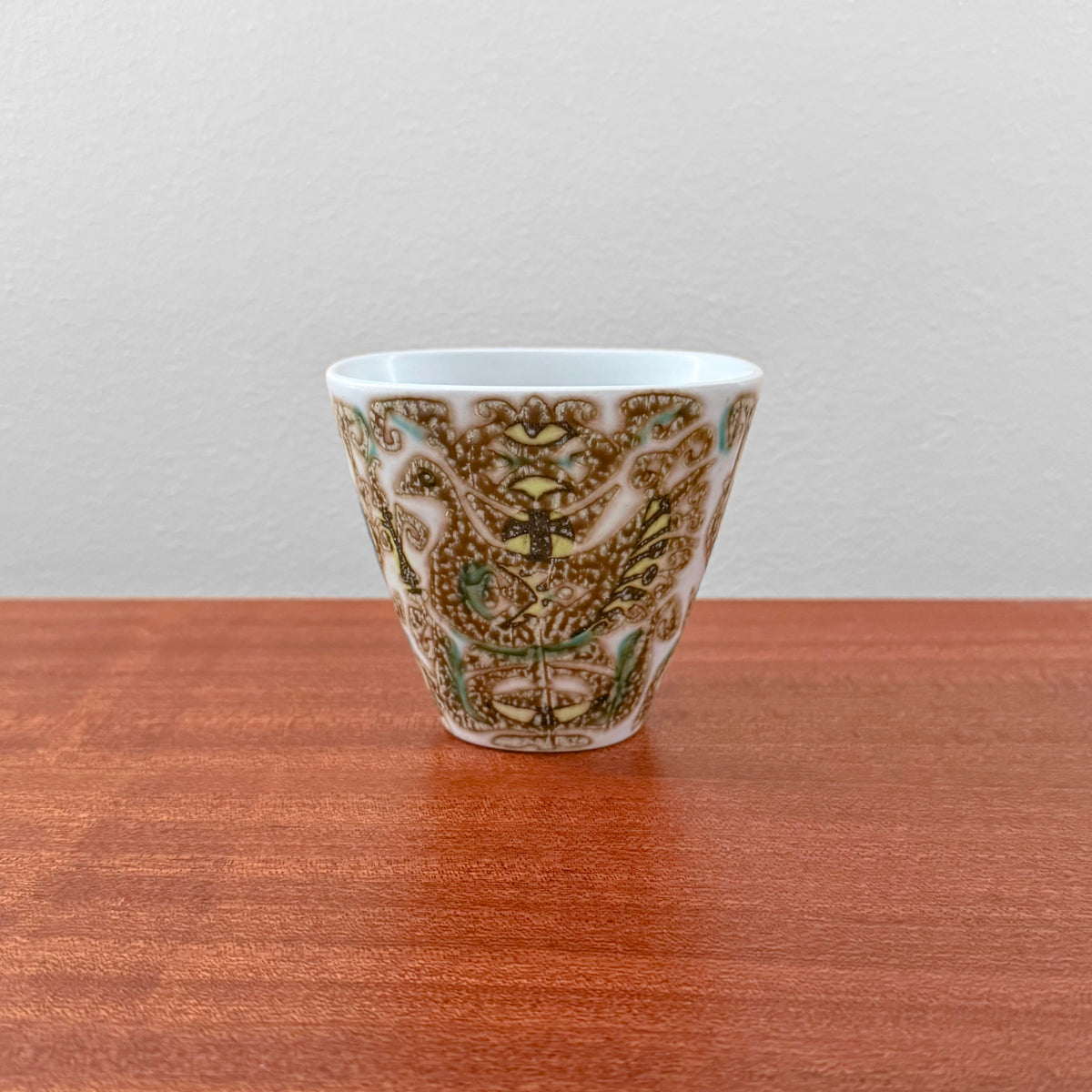 Nils Thorsson Royal Copenhagen Baca Small Vase (713/3216), ceramic vase with stylised bird motif in brown and green on a wooden surface.