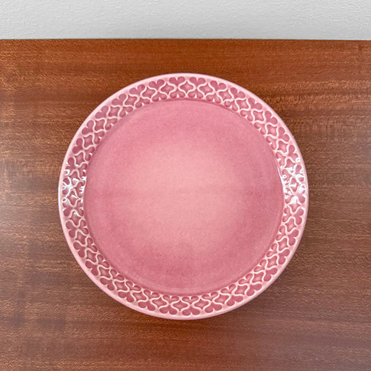 Quistgaard Cordial Palet Pink Tea Cup Trio Set cake plate with a vintage pink ceramic finish and decorative heart pattern around the edge, displayed on a wooden surface.