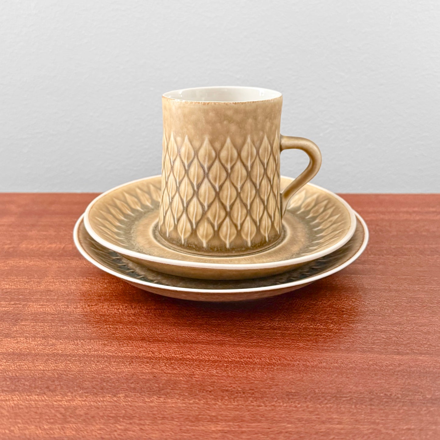 Quistgaard Relief Coffee Cup Trio Set featuring a vintage ceramic coffee cup with textured geometric relief, paired with matching saucer and cake plate in earthy tones.