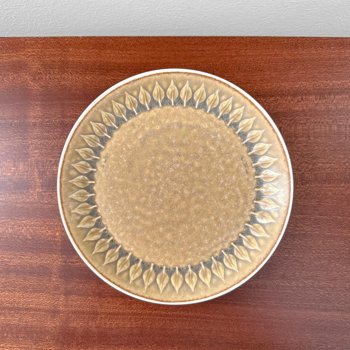 Quistgaard Relief Coffee Cup Trio Set cake plate with vintage textured relief pattern featuring leaf motifs in earthy tones on a wooden surface.