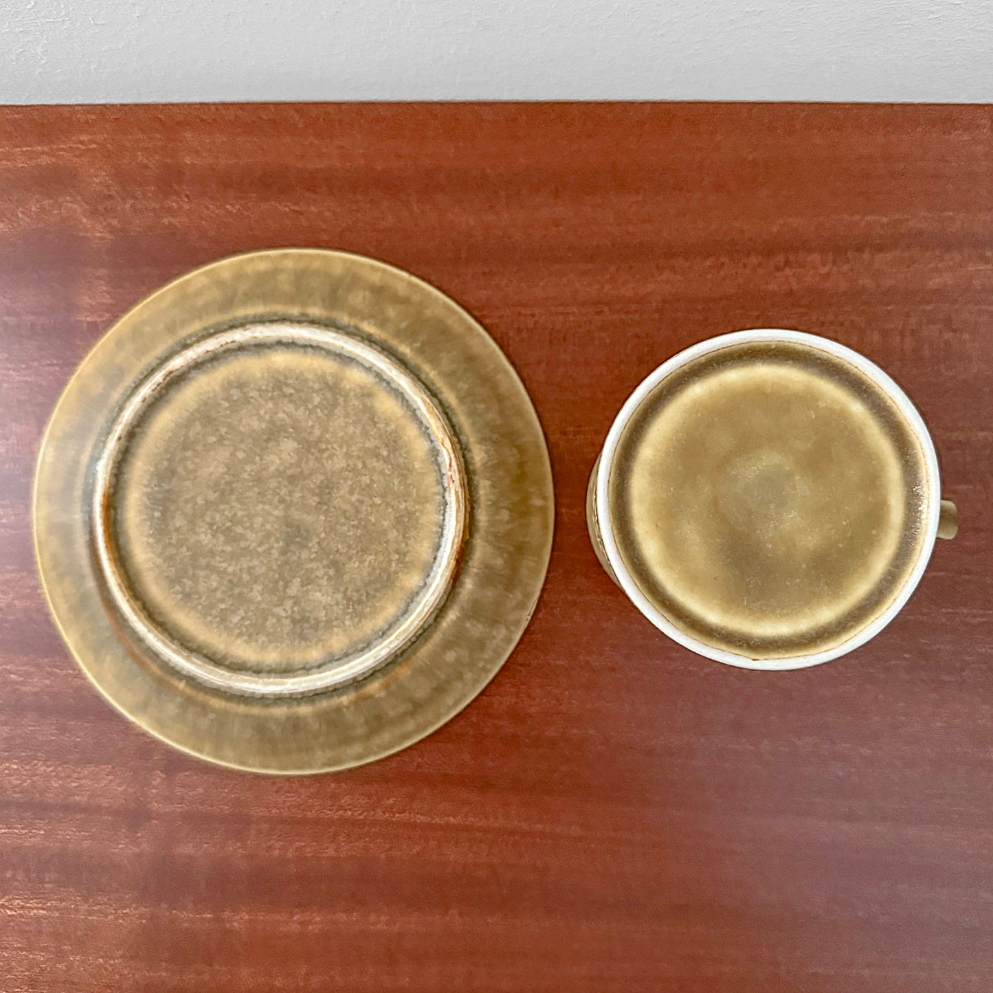 Quistgaard Relief Coffee Cup Trio Set showing vintage ceramic cup and saucer with textured relief design in earthy brown tones on wooden surface.
