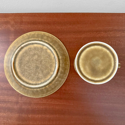 Quistgaard Relief Coffee Cup Trio Set showing vintage ceramic cup and saucer with textured relief design in earthy brown tones on wooden surface.