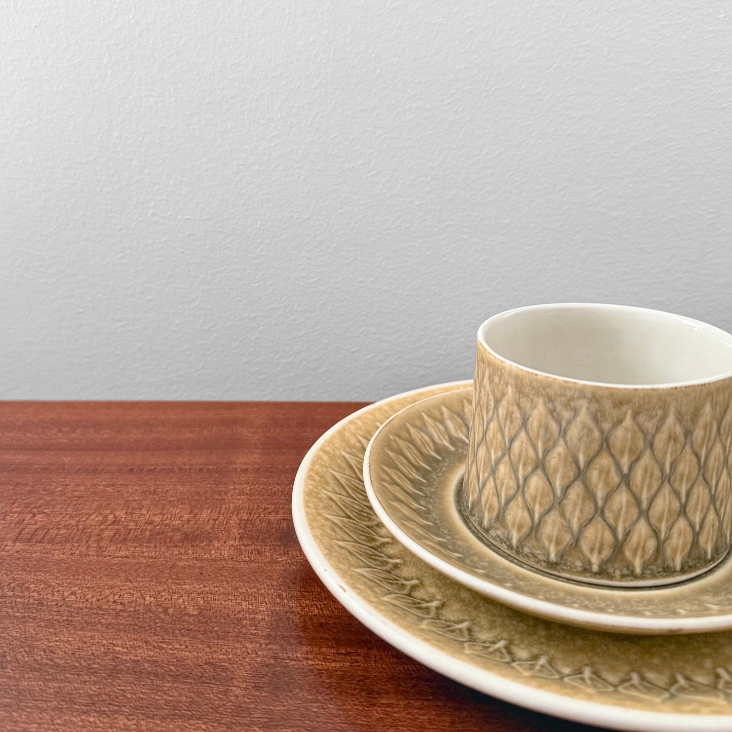 Quistgaard Relief Tea Cup Trio Set with Large Cake Plate featuring textured ceramic drinkware with intricate vintage Nordic design on a wooden surface against a plain background.