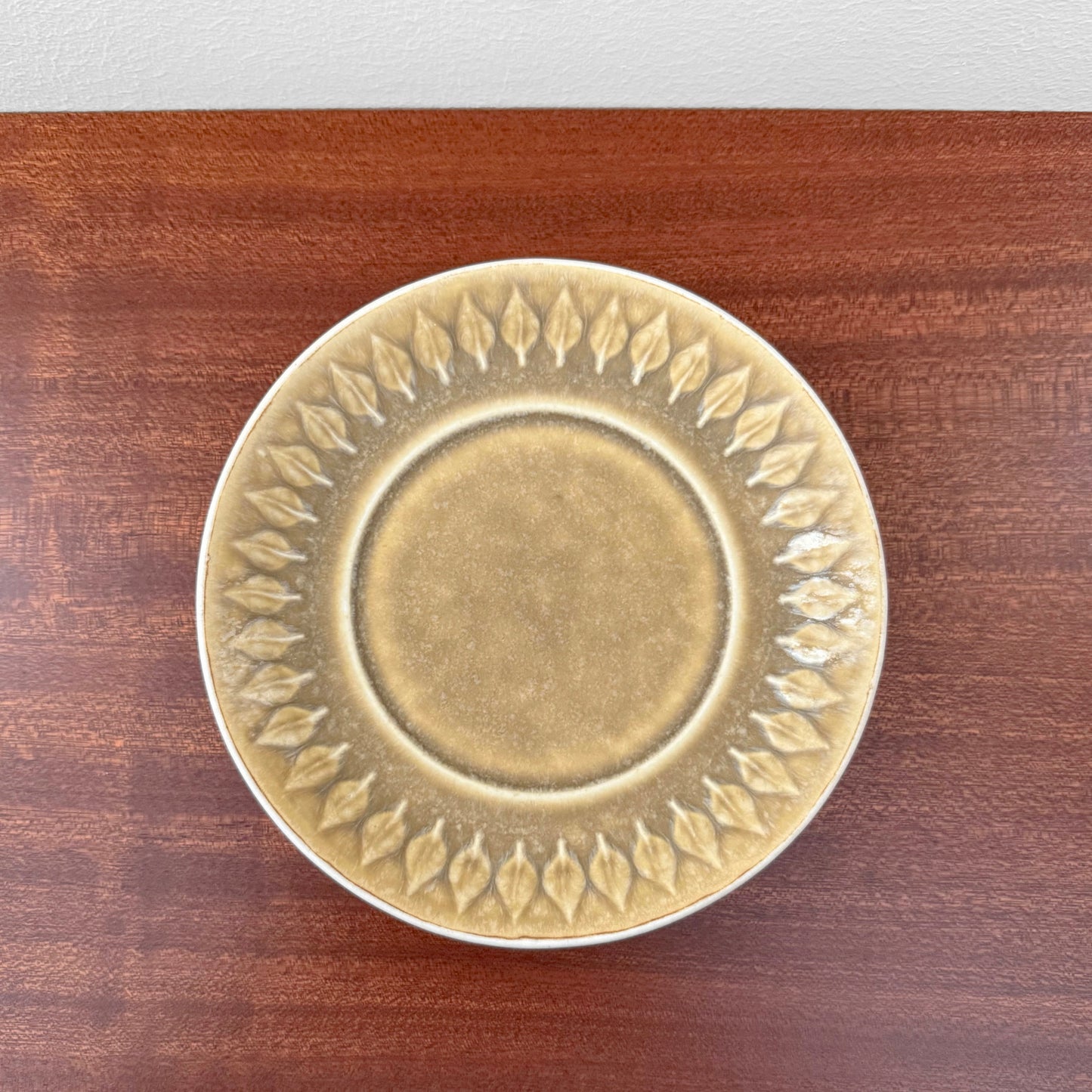 Quistgaard Relief Tea Cup Trio Set with Large Cake Plate featuring a vintage ceramic saucer with raised leaf pattern in warm earthy tones on a wooden surface.