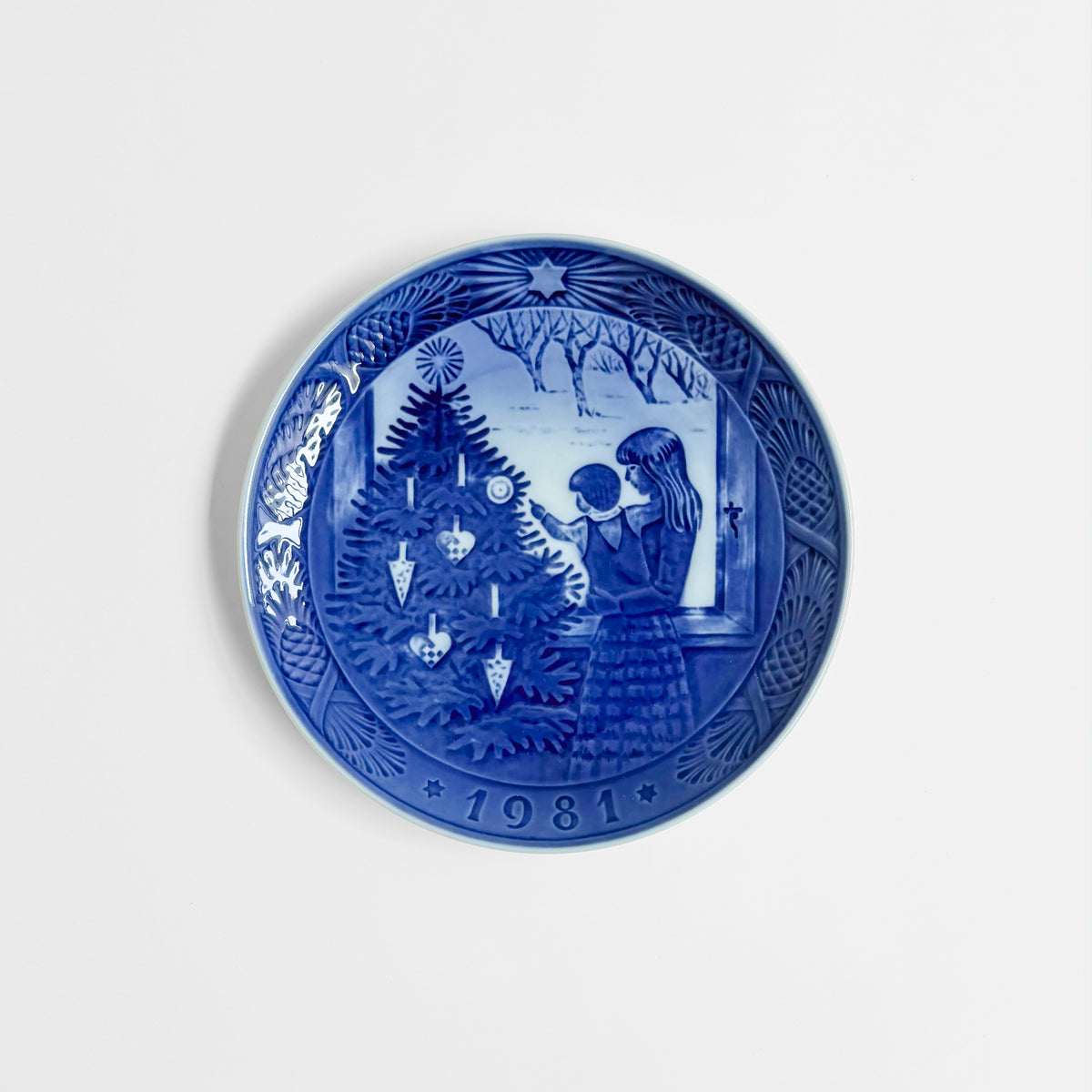 Royal Copenhagen Christmas Plates blue and white ceramic decorative plate depicting a child beside a Christmas tree with 1981 date and detailed Nordic border
