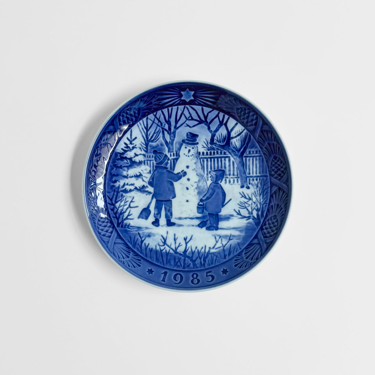 Royal Copenhagen Christmas Plates decorative dish in blue and white with children building a snowman in a winter scene and 1985 date around the rim