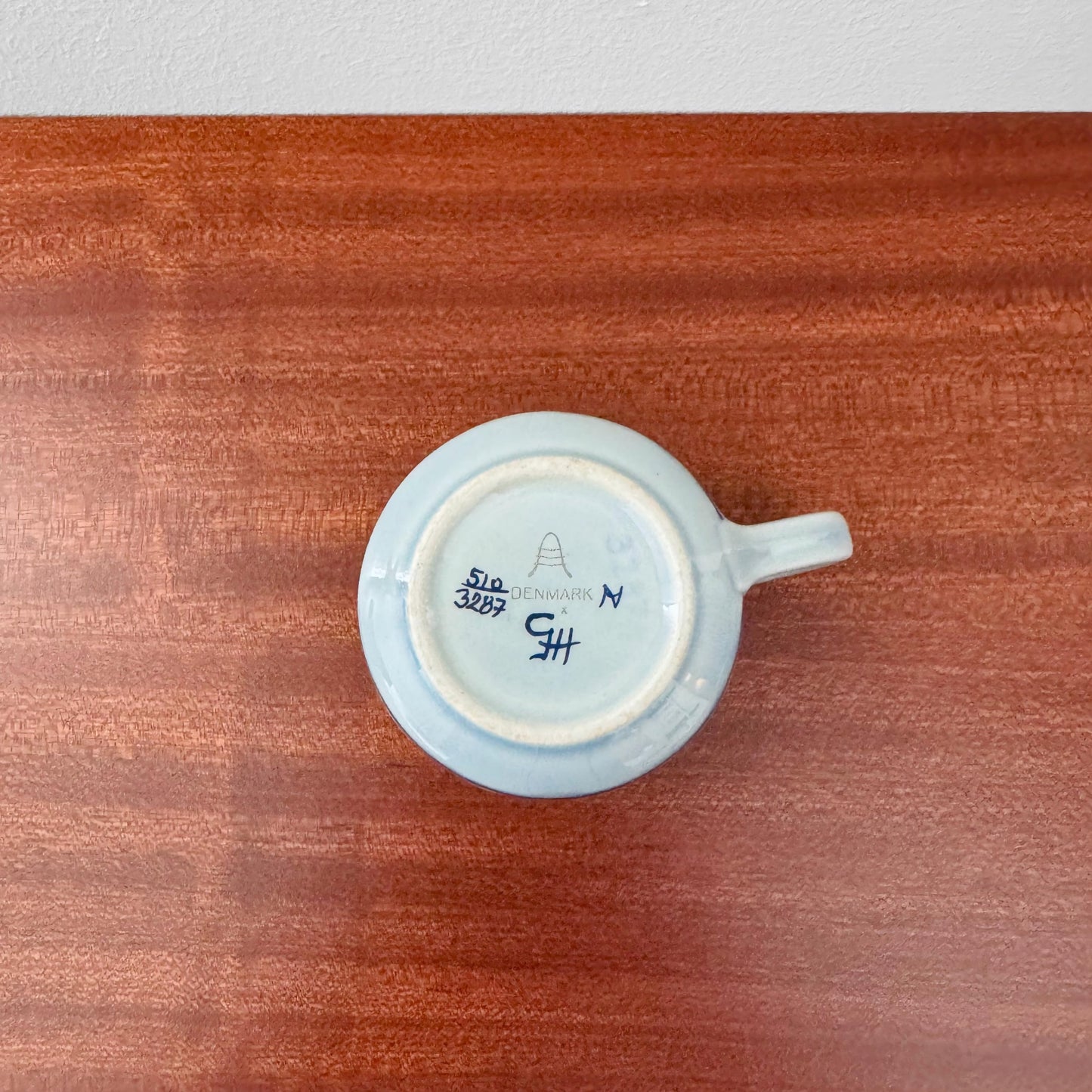 Royal Copenhagen Tenera Coffee Cup (510/3287) shown from below on a wooden surface with maker marks and pale blue glazed ceramic.