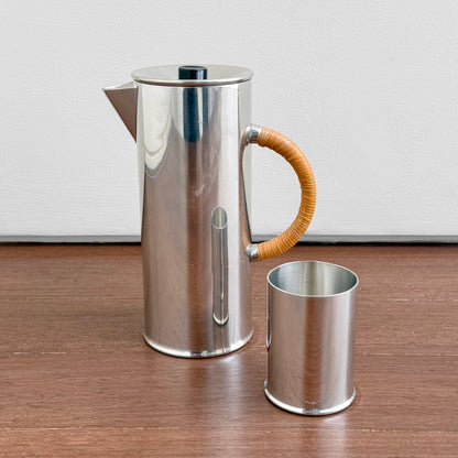 Royal Selangor Erik Magnussen Pewter Coffee Set featuring a tall pewter coffee pot with a woven handle and a matching pewter cup, displayed on a wooden surface against a white background.