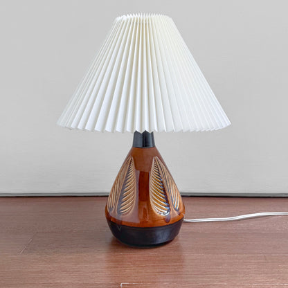 Søholm 1049 Brown-Black Stoneware Table Lamp with leaf relief, brown and black glaze, and a white pleated shade on a wooden surface