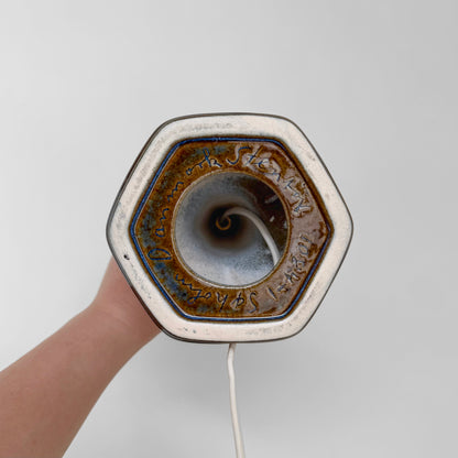 Bottom view of the Søholm 1084 Blue Stoneware Table Lamp showing the hexagonal ceramic base with a blue glaze interior and an inscription, held by a hand against a plain background.