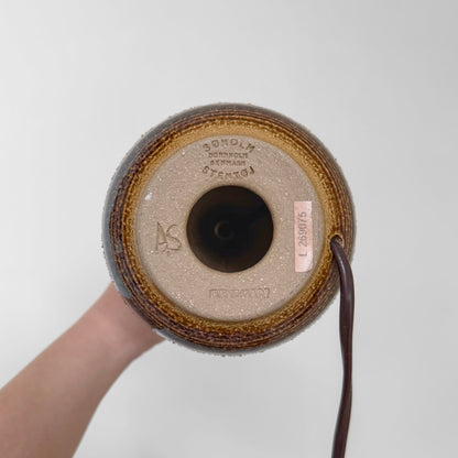 Bottom view of the Søholm Black-Brown Stoneware Table Lamp showing the ceramic base with maker's stamp, signature 'AS', and attached electrical cord.
