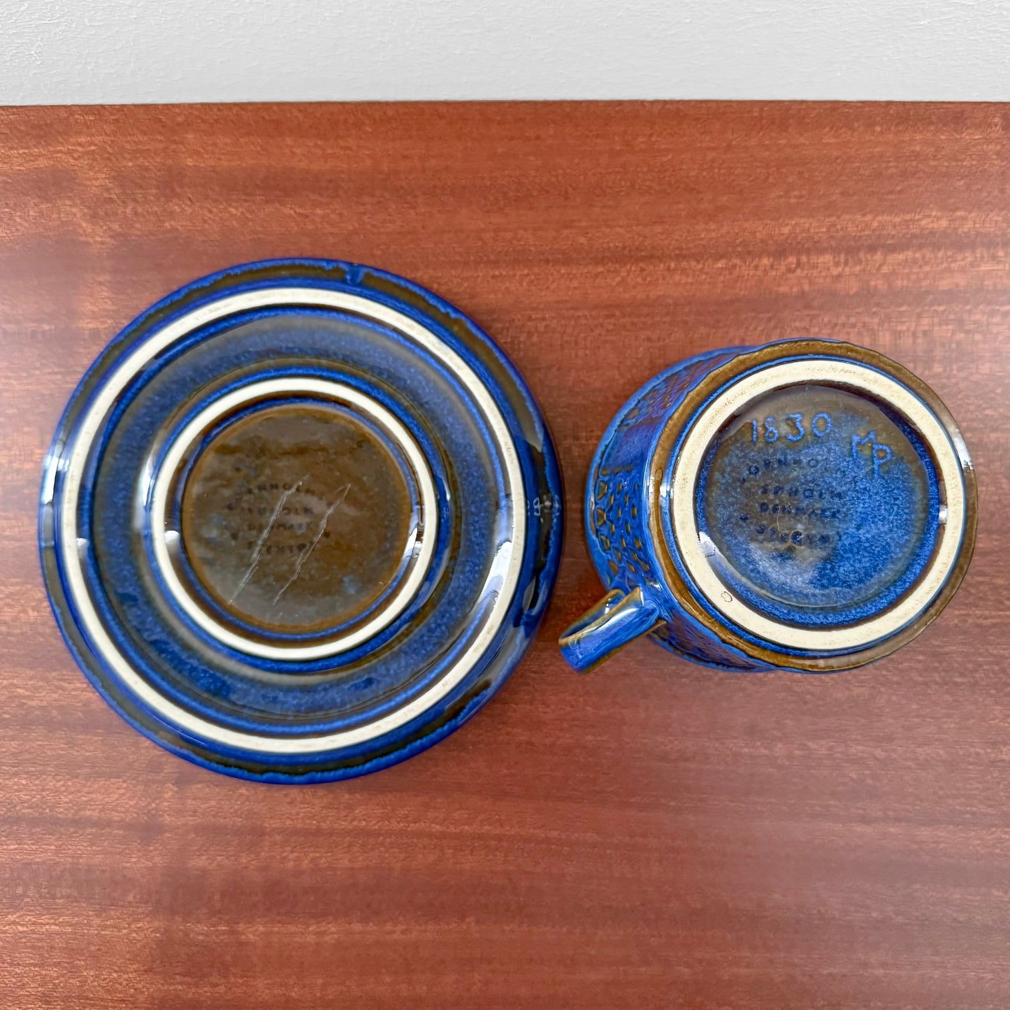 Søholm Granit Blue Tea Cup with Saucer shown from the bottom, highlighting vintage blue ceramic with textured glaze and maker's marks, reflecting Scandinavian craftsmanship.