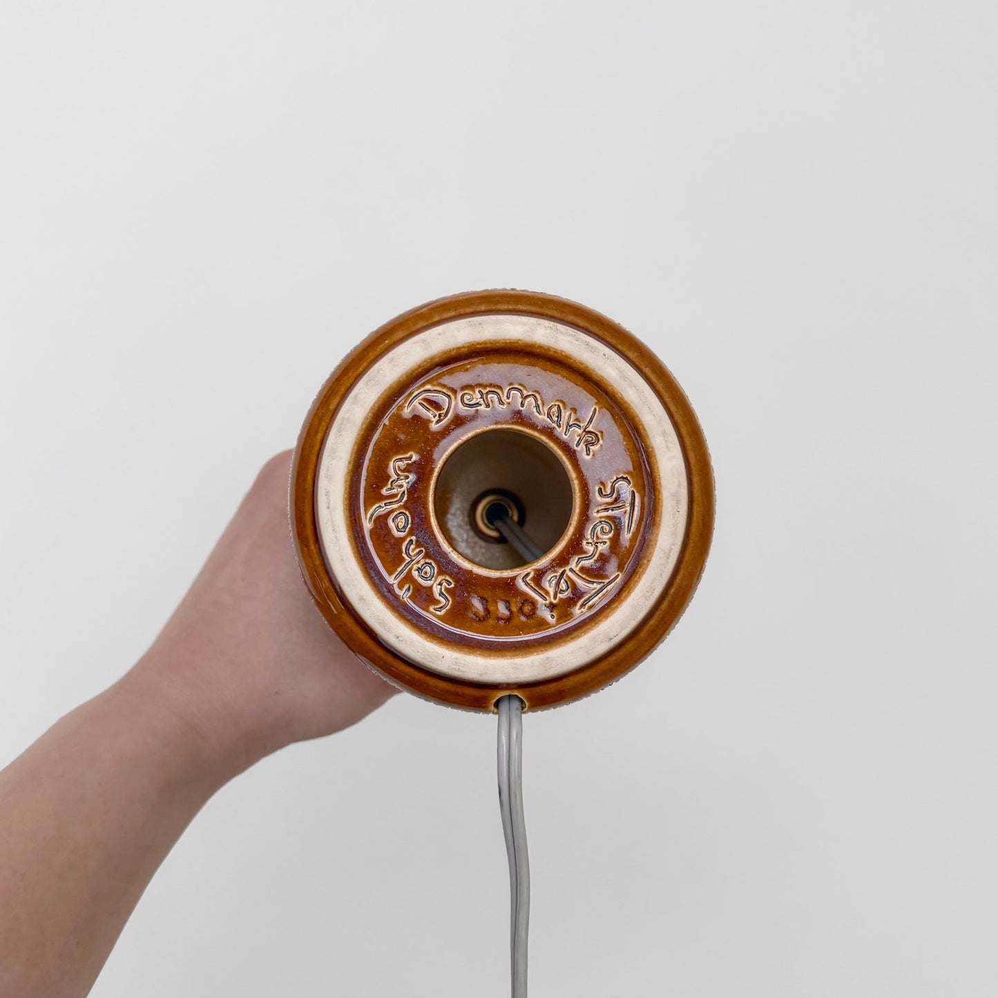 Bottom view of Søholm Manilla Small Brown Stoneware Table Lamp showing circular ceramic base with Denmark marking and attached power cord.