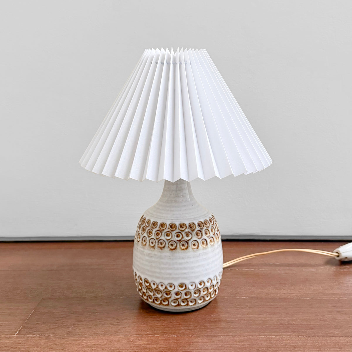Søholm White Stoneware Table Lamp with a textured white ceramic base and pleated shade displayed on a wooden surface